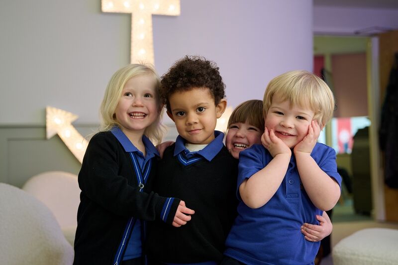 A group of 4 young school children in black and blue uniforms all smiling