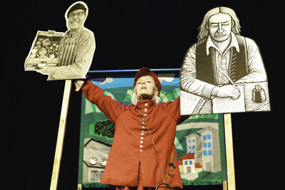 Victoria Melody stands with two cut-outs of historical figures raised about her head