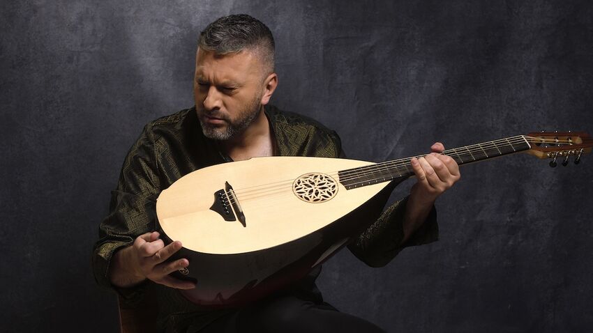 Damir Imamovic sits holding a wooden instrument with his eyes closed