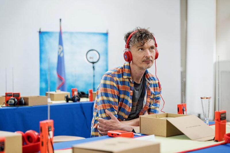 Picture of someone sat at a table and listening to a radio