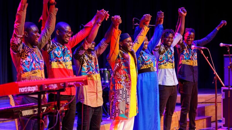 Seckou Keita and his Homeland Band in a row ready to take a bow, holding hand together above their heads