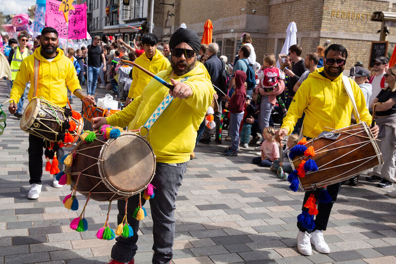 A group of professional musicians parade along New Road. They play traditional Indian drums