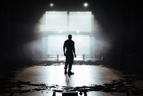 A silhouette of a man looking toward a grid of four white squares, representing a window