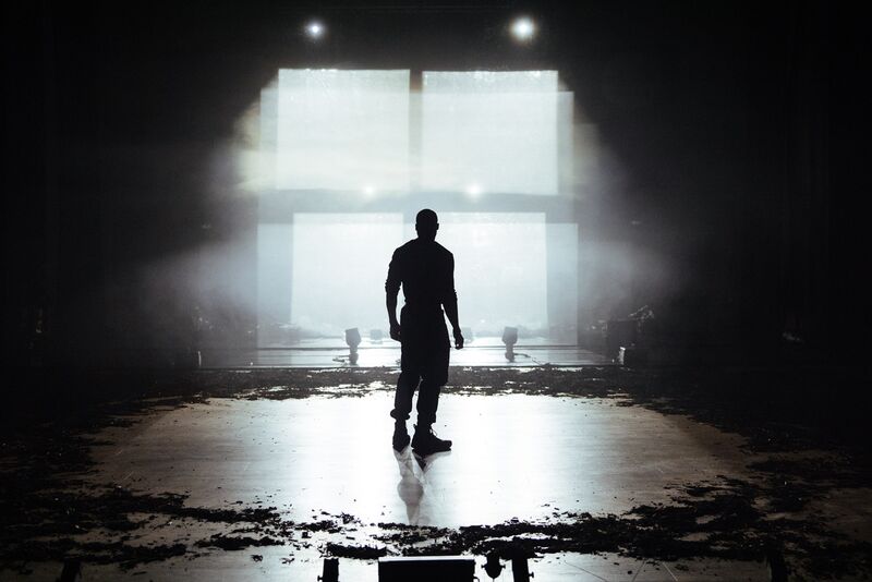 A silhouette of a man looking toward a grid of four white squares, representing a window
