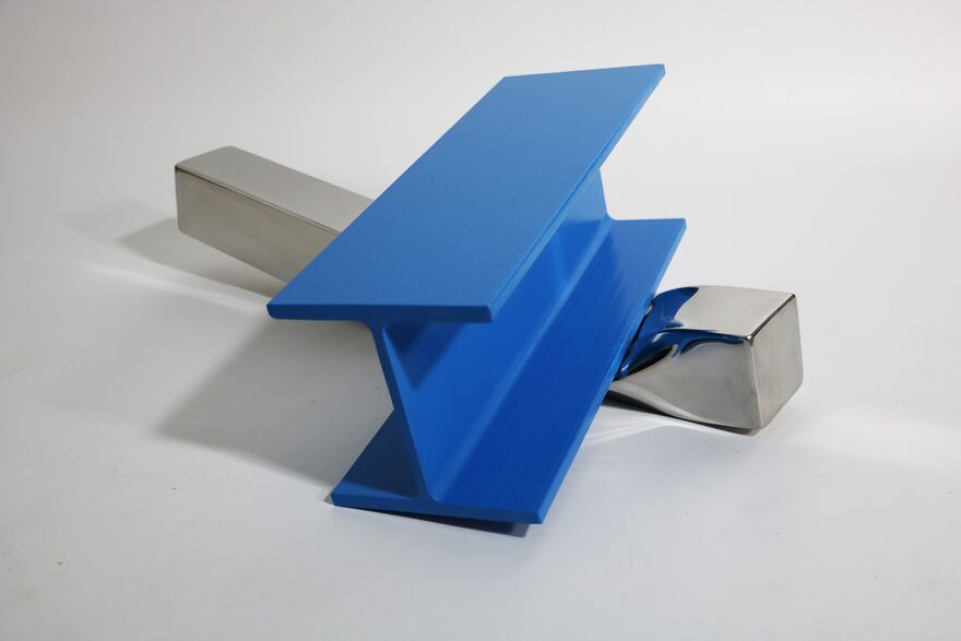 A sculpture of a rectangular piece of metal being squashed by a big blue iron structure