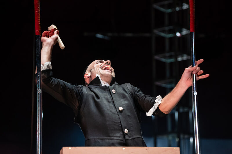A bald man in a black shirt laughs maniacally