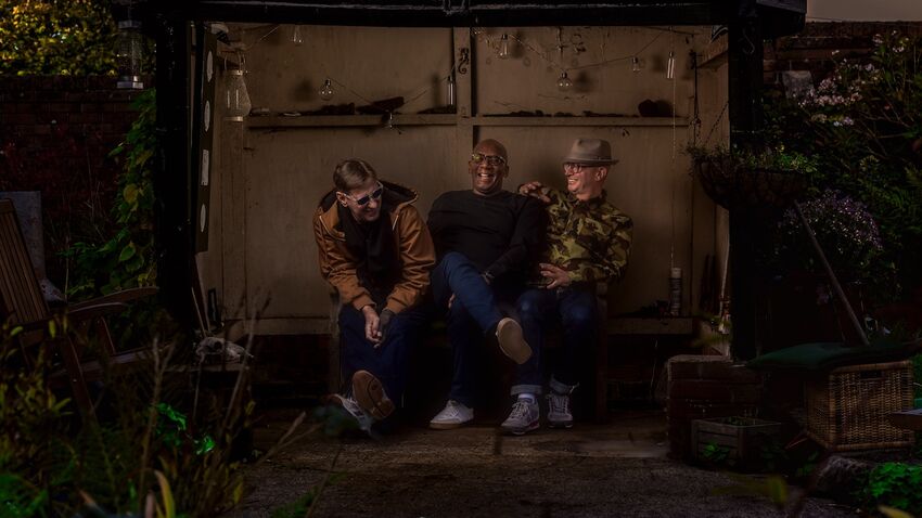 A Certain Ratio sit laughing in a garden