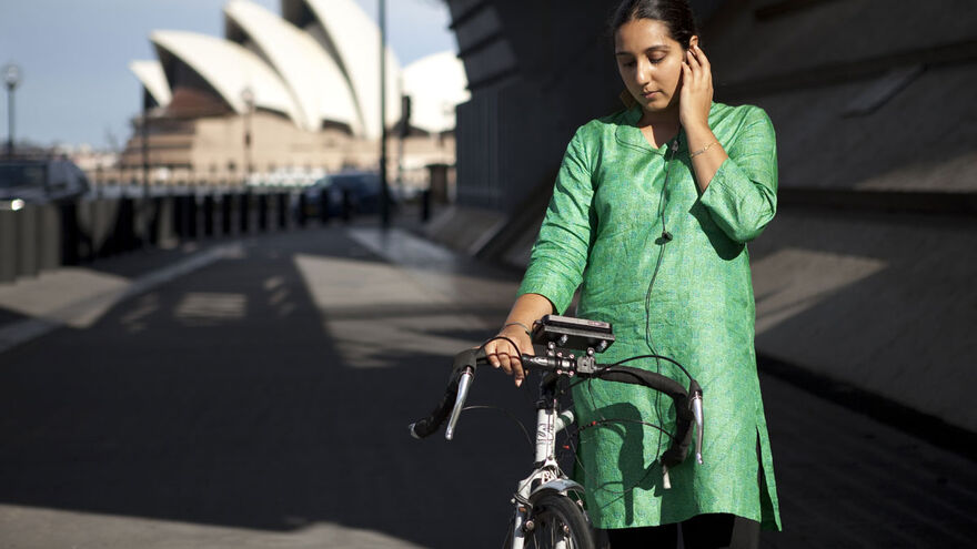 A woman listens to headphones as she stands next to a bike