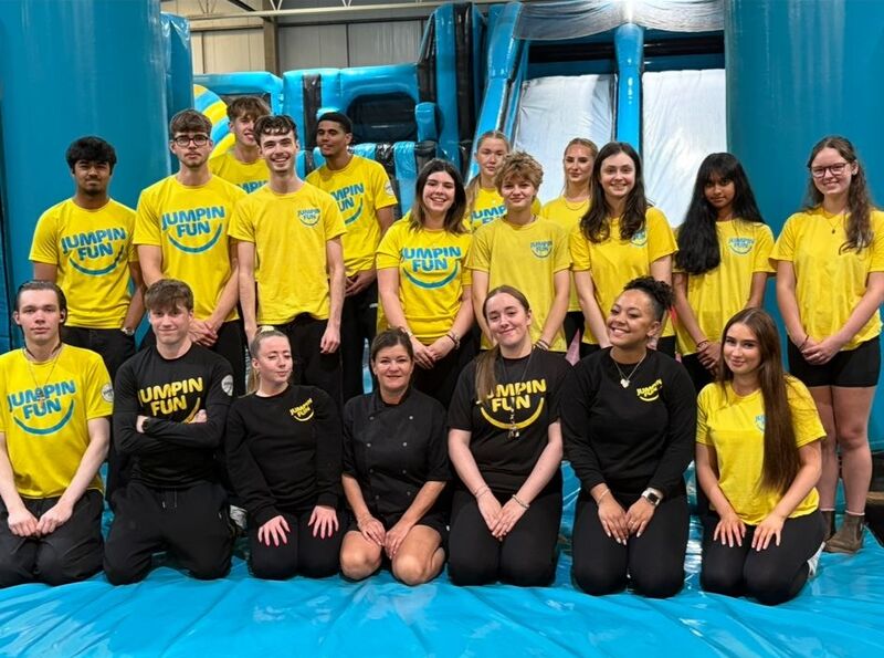 A group of young adults in yellow and black uniform all grouped together in an inflatable fun park