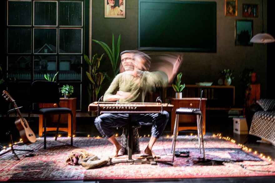 Aditya Prakash plays a double-headed drum, alarge projection of his face behind him