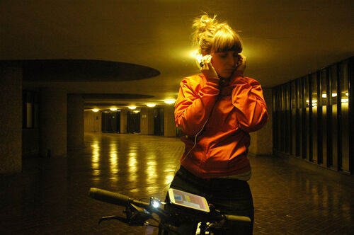A woman listens to headphones on a bike at the Barbican Centre